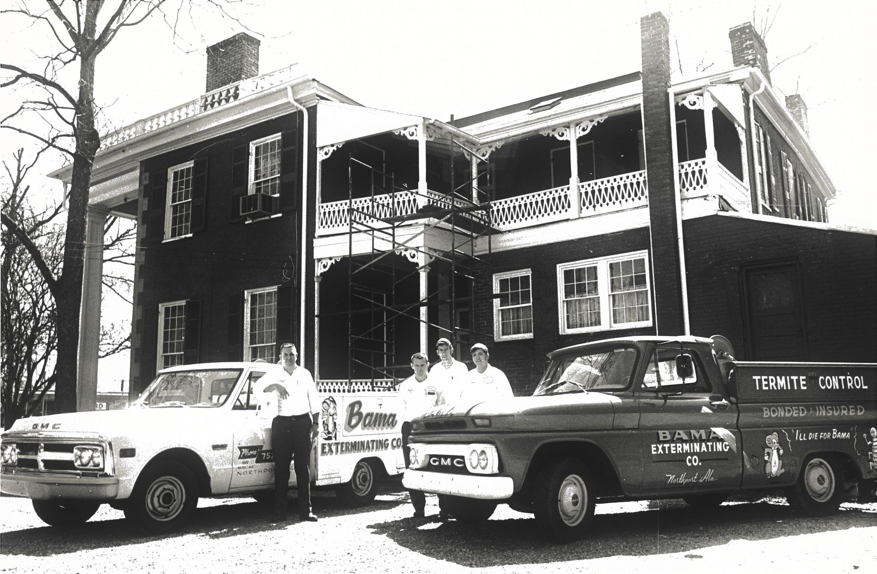 Bama technicians with two GMC termite control trucks at a historic brick home