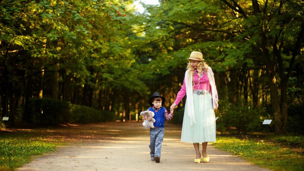 Mother and son walking together down a sunlit path