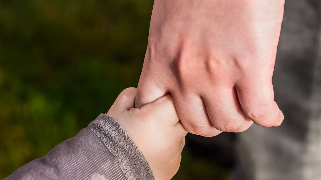 Close up of a child holding an adult's hand